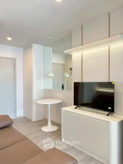 Modern living room with sleek furniture and stylish decor, featuring a TV and elegant lighting.