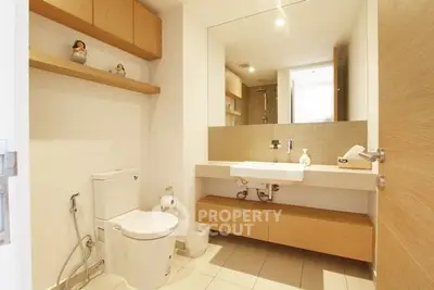 Modern bathroom with sleek fixtures and wooden accents, featuring a large mirror and ample storage.