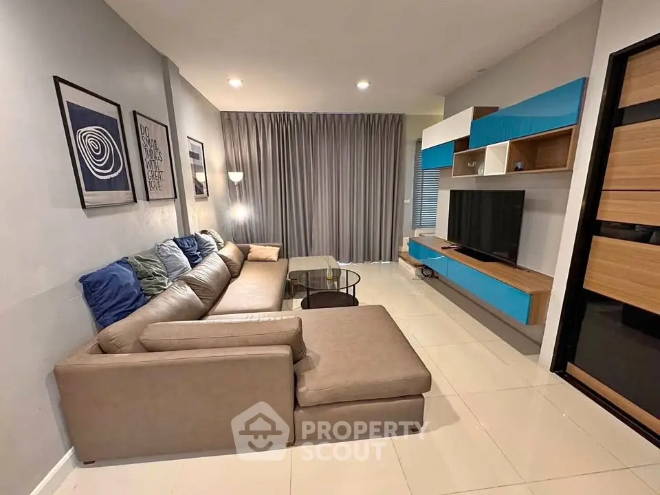 Modern living room with stylish sectional sofa and wall-mounted TV unit.