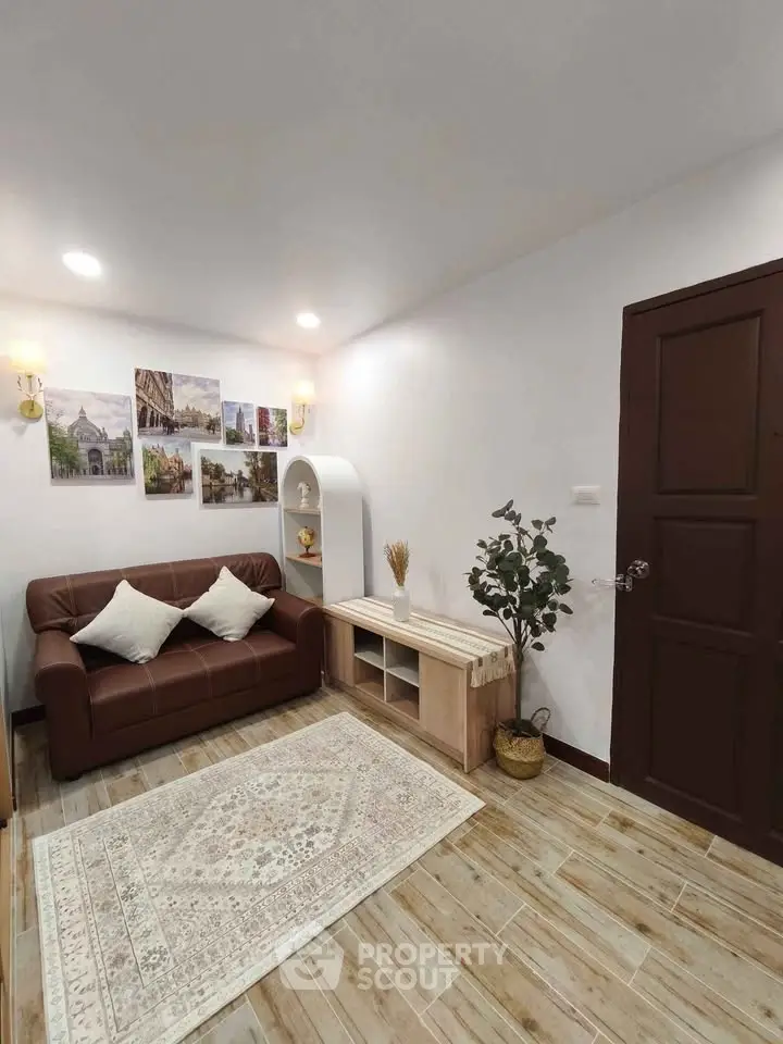 Cozy living room with brown sofa, decorative wall art, and wooden flooring for a warm ambiance.