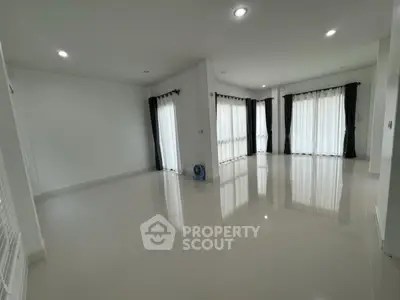 Spacious empty living room with large windows and glossy tiled floors