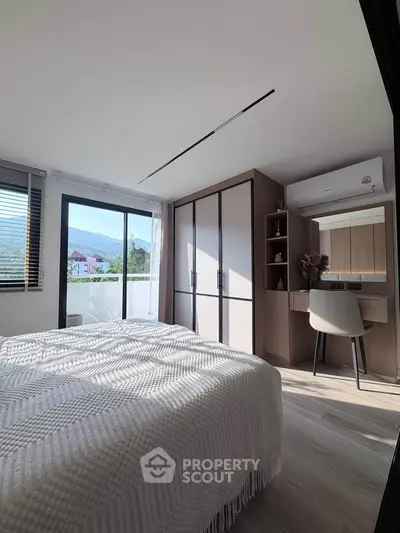 Modern bedroom with mountain view, featuring sleek furniture and natural light.