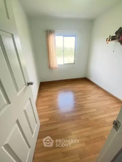 Bright empty bedroom with wooden flooring and window view