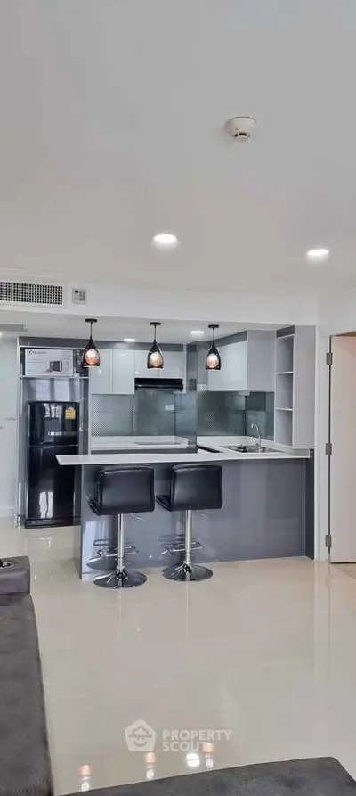 Modern kitchen with sleek design, featuring a breakfast bar and stylish pendant lights.