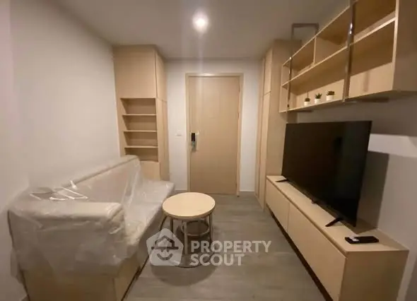 Modern living room with sleek furniture and large TV in a cozy apartment setting.
