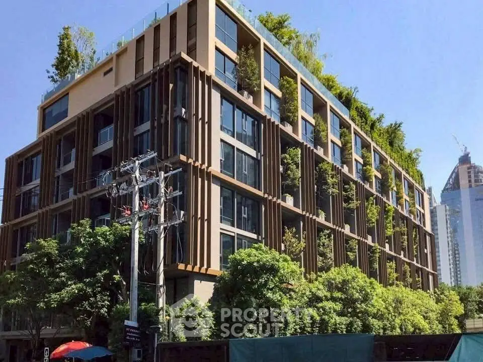 Modern eco-friendly building with lush greenery and urban skyline view.