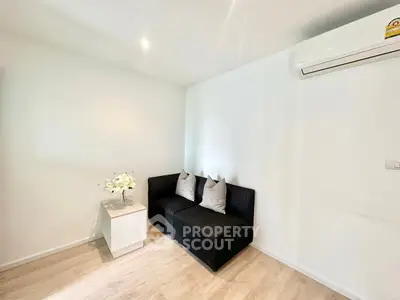 Cozy living room with modern black sofa and air conditioning, perfect for relaxation.