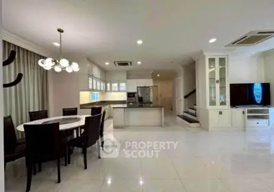Spacious open-plan living and dining area with modern kitchen and elegant lighting.