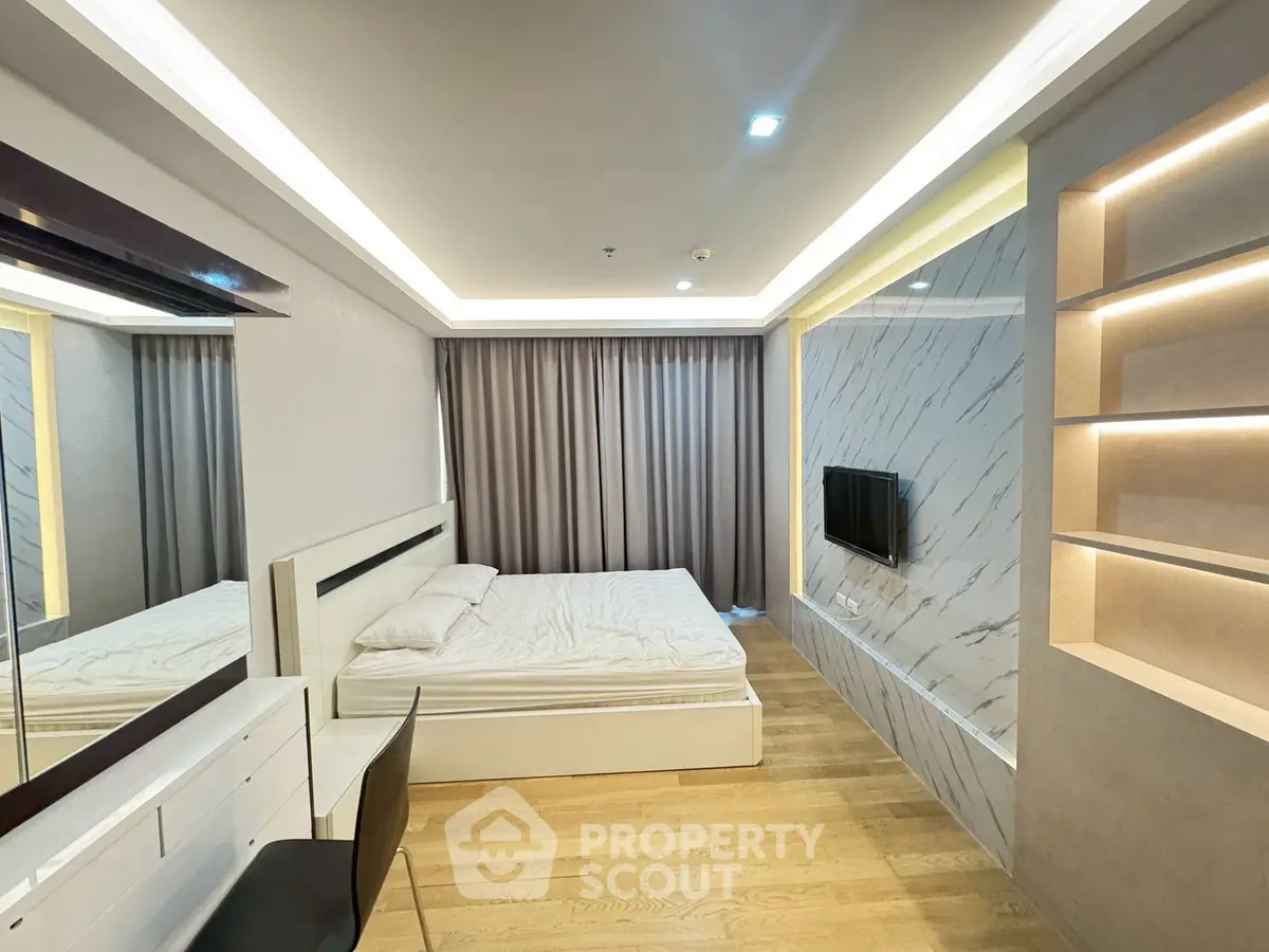 Modern bedroom with sleek design, wooden flooring, and built-in TV for ultimate comfort.