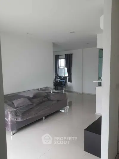 Modern living room with sleek furniture and open layout, featuring a cozy sofa and dining area.