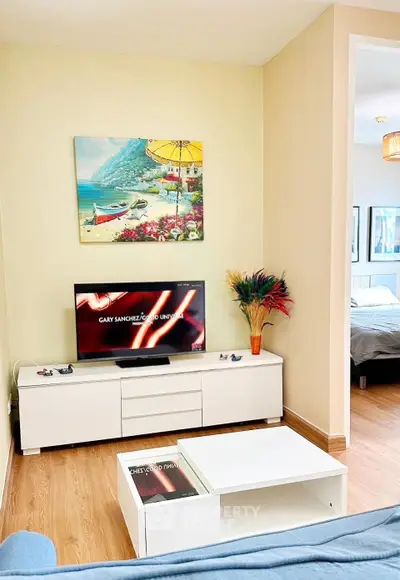 Charming living room with modern decor and cozy ambiance, featuring a stylish TV setup and vibrant artwork.