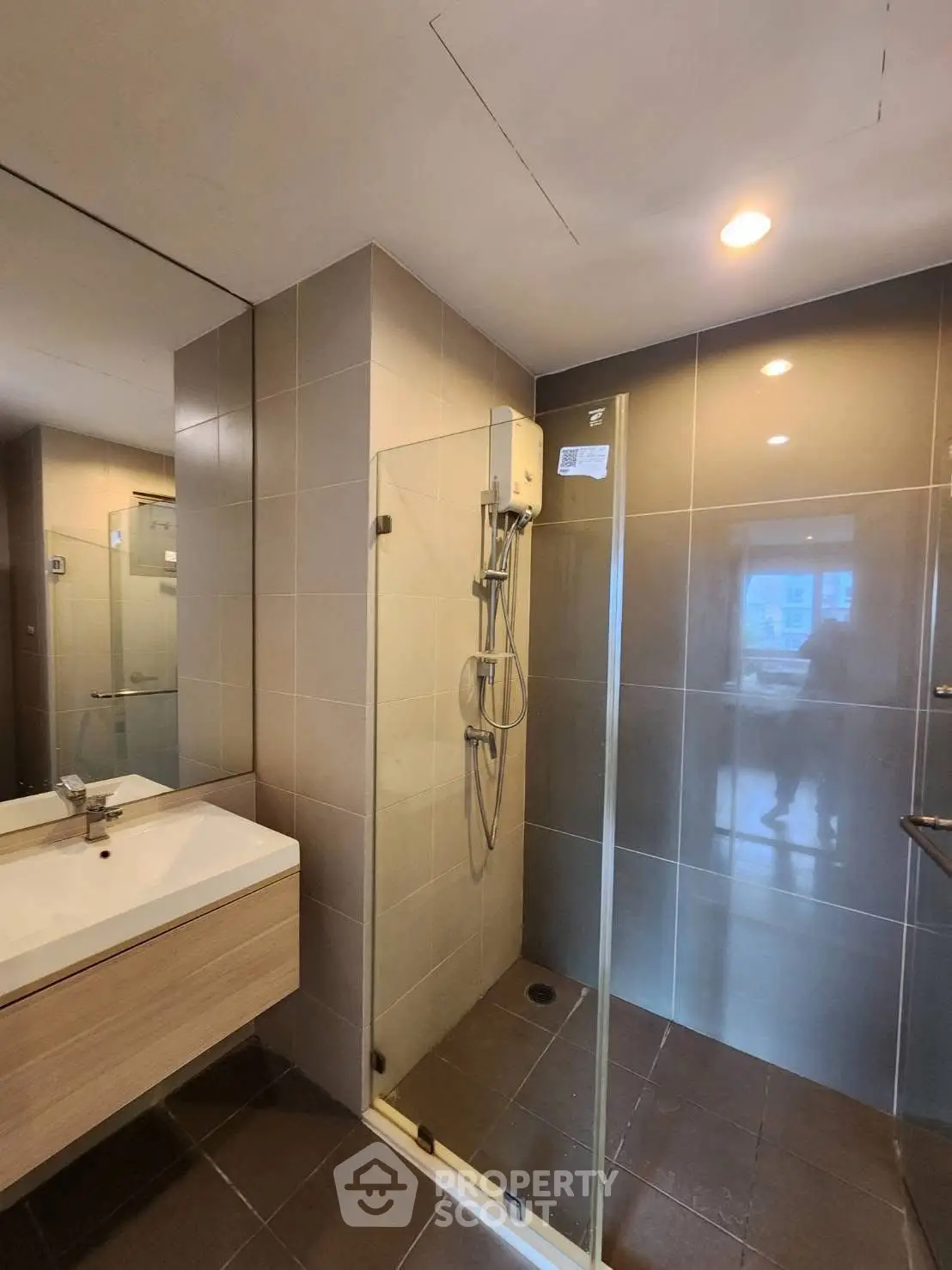 Modern bathroom with glass shower and sleek vanity in contemporary apartment.