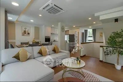 Modern living room with open kitchen, stylish decor, and cozy seating area.