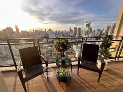 Stunning city view from a high-rise balcony with cozy seating and lush plants, perfect for relaxation.