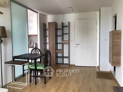 Modern apartment interior with wooden flooring, dining area, and open shelving.