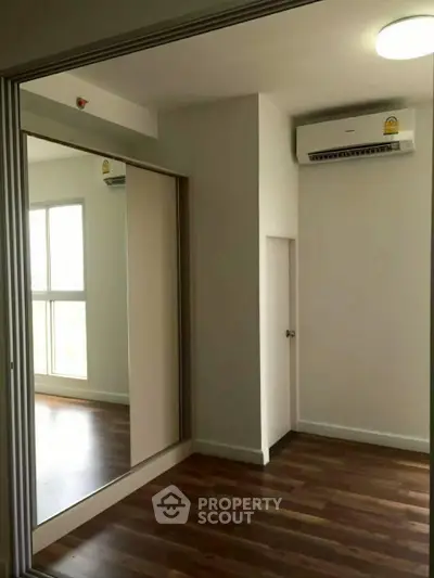 Modern bedroom with wooden flooring and mirrored closet doors