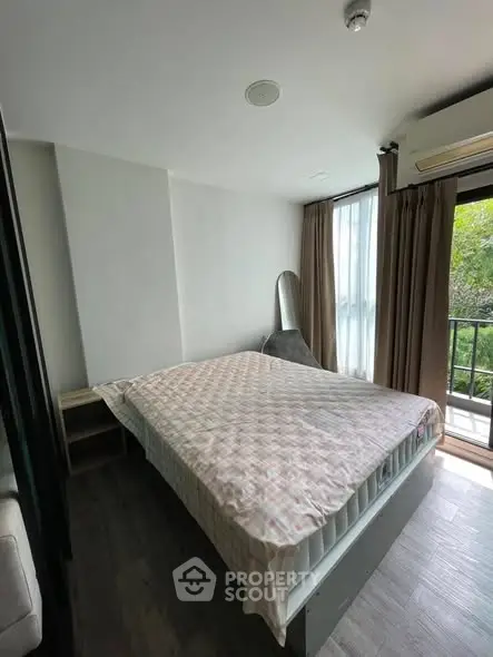Cozy bedroom with balcony view and natural light, featuring modern decor and air conditioning.