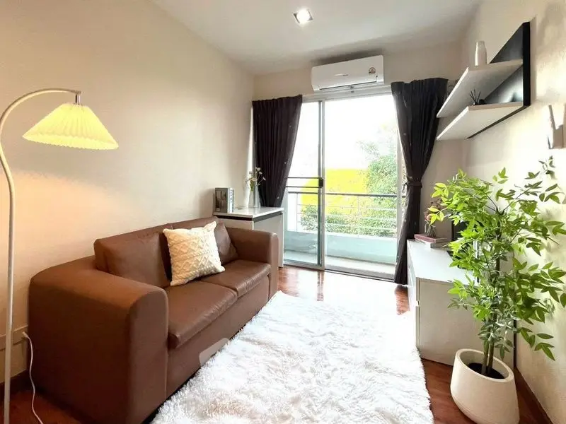 Cozy living room with brown sofa, white rug, and balcony view
