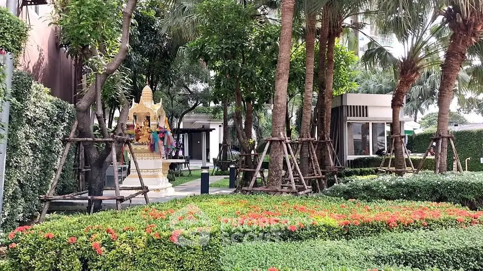 Lush garden area with vibrant flowers and trees in a residential complex.