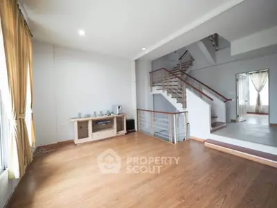 Spacious living room with wooden floors and modern staircase in a bright, airy home.