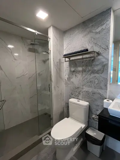 Modern bathroom with sleek design, featuring glass shower and elegant marble tiles.