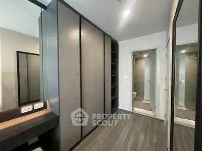 Modern bedroom with sleek wardrobe and en-suite bathroom in contemporary apartment.