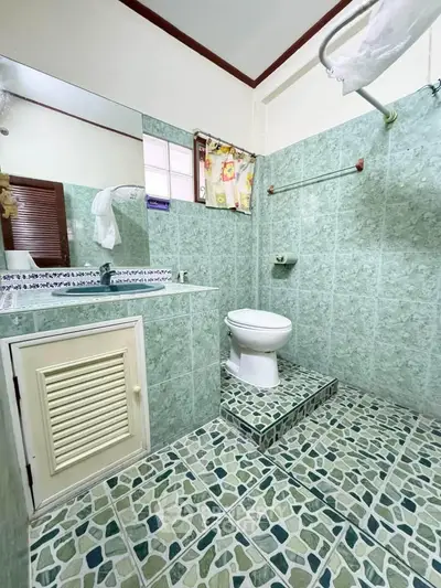 Charming bathroom with green tile design and elevated toilet area
