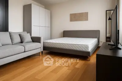 Modern bedroom with sleek furniture and wooden flooring, featuring a comfortable bed and stylish sofa.