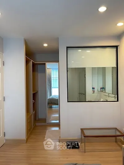 Modern apartment interior with wooden flooring and glass partition, showcasing a cozy bedroom view.