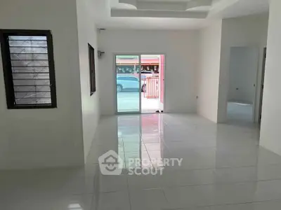 Spacious modern living room with large windows and sleek white tiles, perfect for natural light and open living.