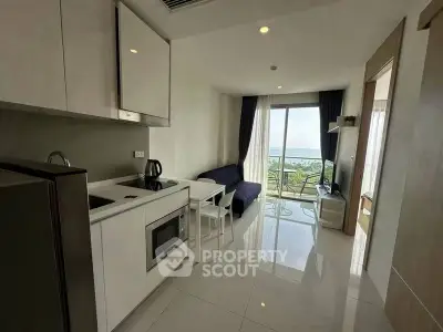 Modern open-plan kitchen and living area with ocean view balcony in stylish apartment.
