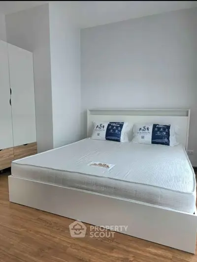 Spacious bedroom with modern white bed and wooden flooring, perfect for relaxation.