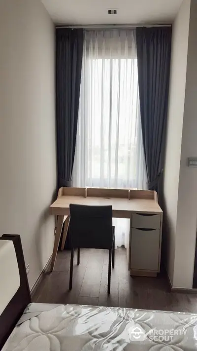 Cozy study nook with desk and chair by a window in modern apartment.