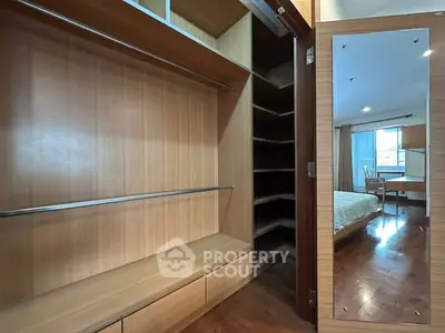 Spacious walk-in closet with wooden shelves and mirror in modern bedroom