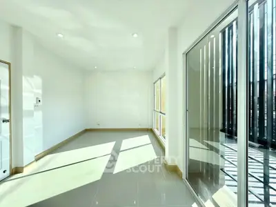 Bright and spacious empty room with large windows and sliding glass doors.