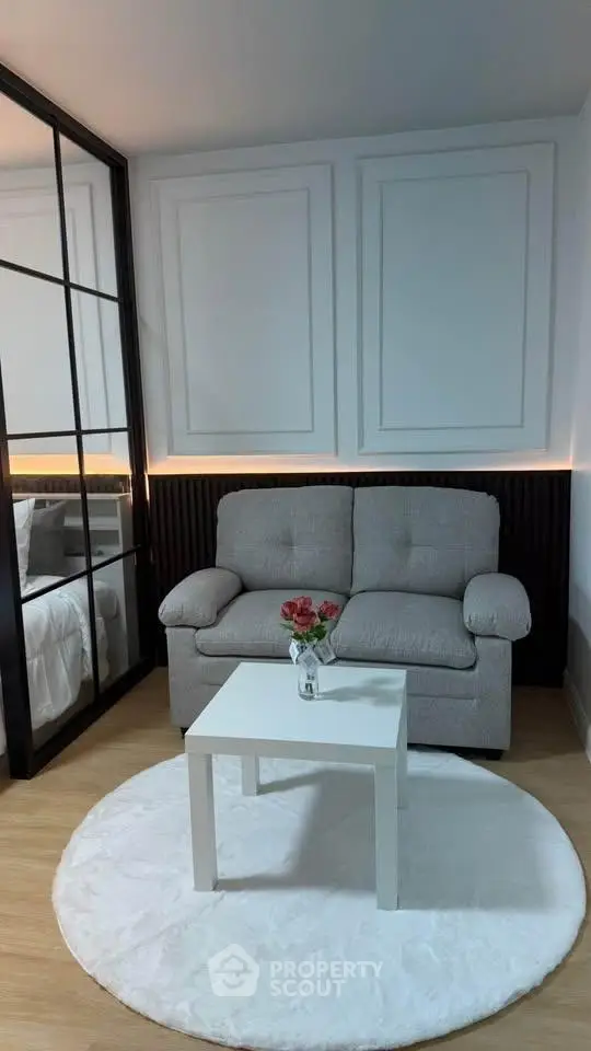 Cozy living room with modern decor and glass partition leading to bedroom