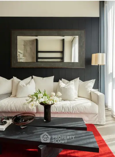Elegant living room with modern decor, featuring a plush white sofa, stylish mirror, and vibrant red rug.