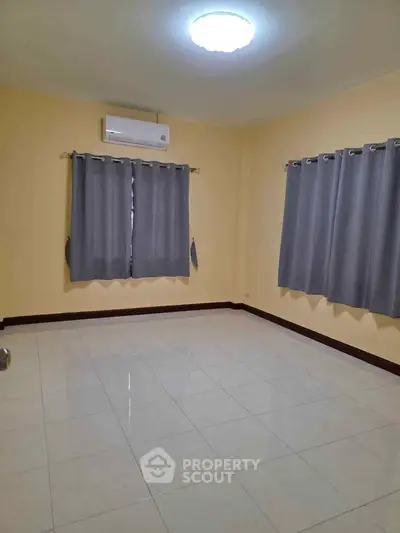 Spacious empty room with tiled floor and air conditioning, ready for customization.