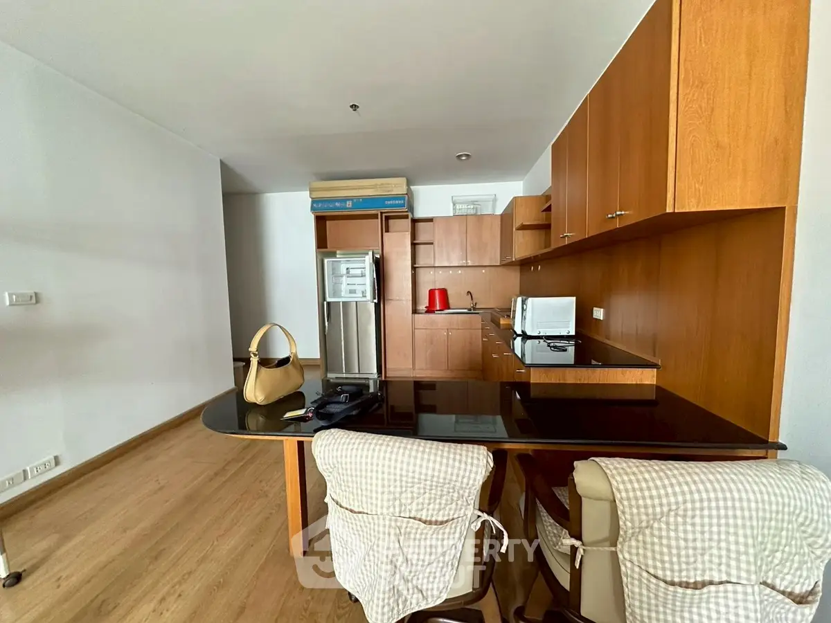 Modern kitchen with wooden cabinets and sleek appliances in a cozy apartment.
