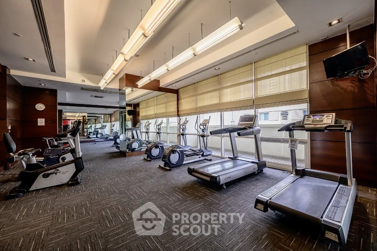 Spacious modern gym with state-of-the-art equipment and large windows for natural light.