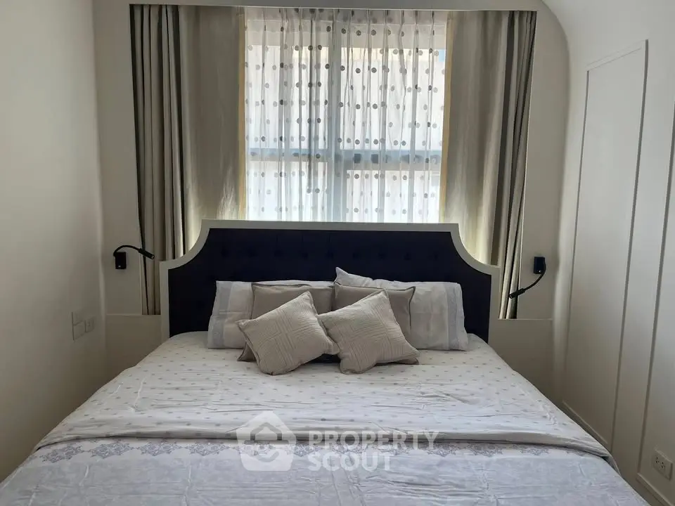 Cozy bedroom with elegant headboard and soft lighting, perfect for relaxation.