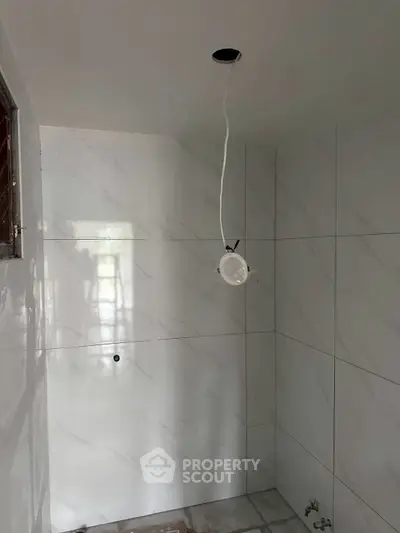 Minimalist bathroom under construction with white marble tiles and exposed wiring.