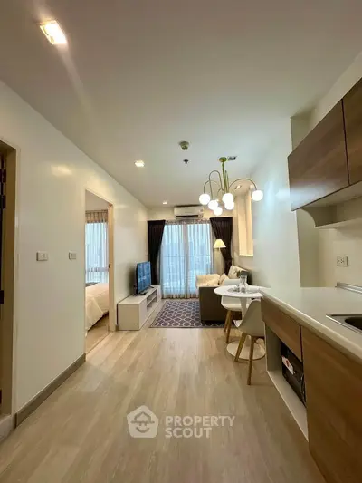 Modern open-plan living room with kitchen, stylish lighting, and cozy seating area in a contemporary apartment.