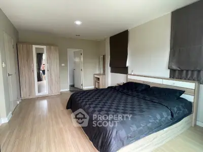 Spacious modern bedroom with sleek wooden flooring and stylish black bedding.