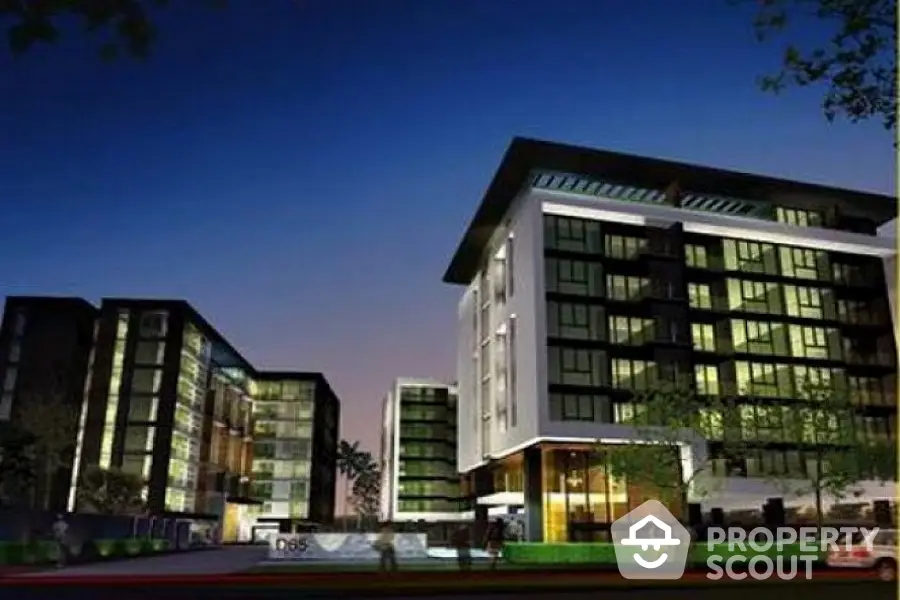 Modern apartment building exterior at dusk with illuminated windows and sleek design.