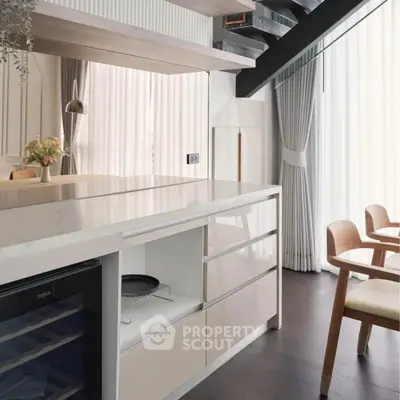 Modern kitchen with sleek cabinetry and natural light, featuring open layout and stylish dining area.