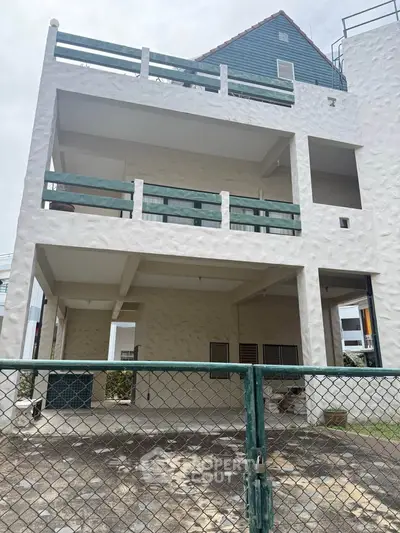 Spacious multi-level building with large balconies and gated entrance, ideal for residential or commercial use.