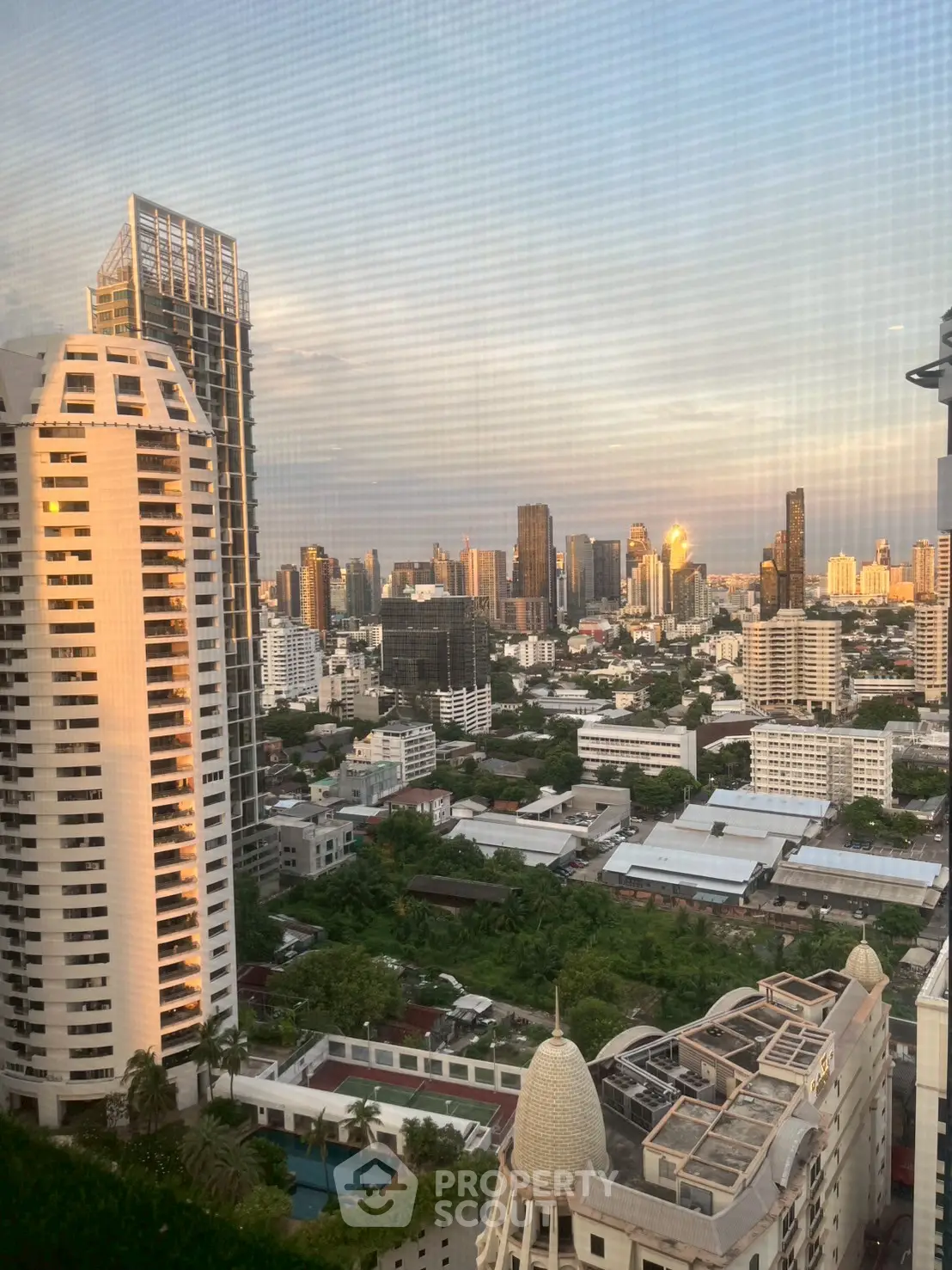 Stunning cityscape view from high-rise building at sunset, showcasing urban skyline and architecture.