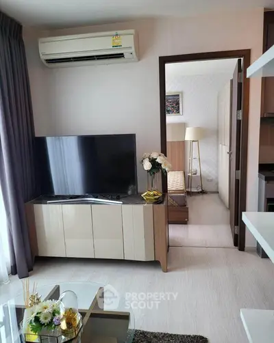 Modern living room with sleek TV unit and view into cozy bedroom