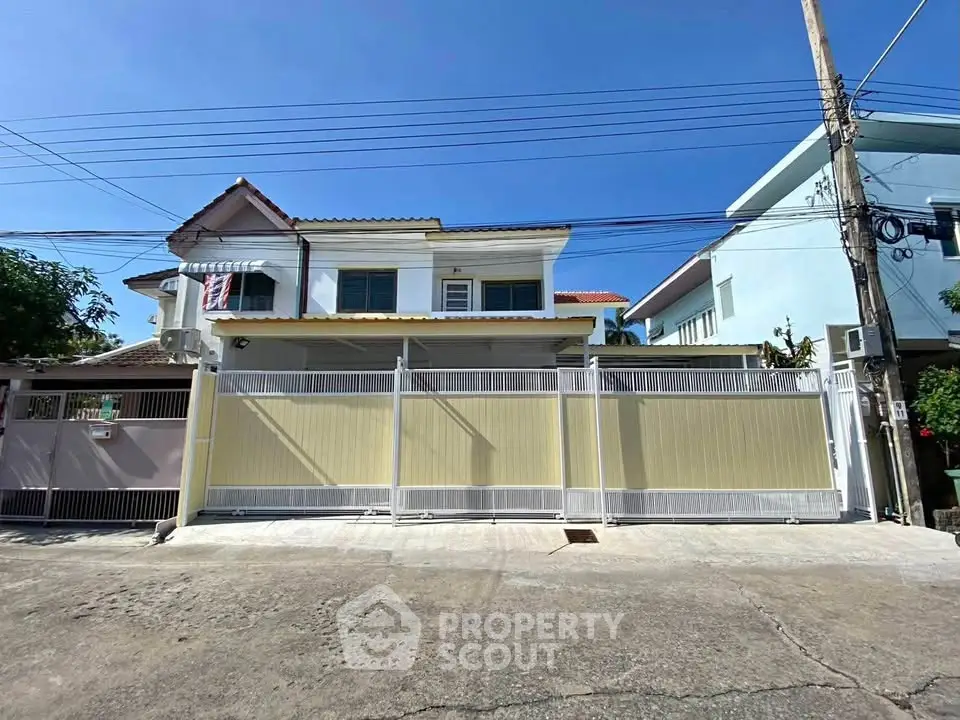 Charming two-story house with gated entrance and sunny exterior in a peaceful neighborhood.